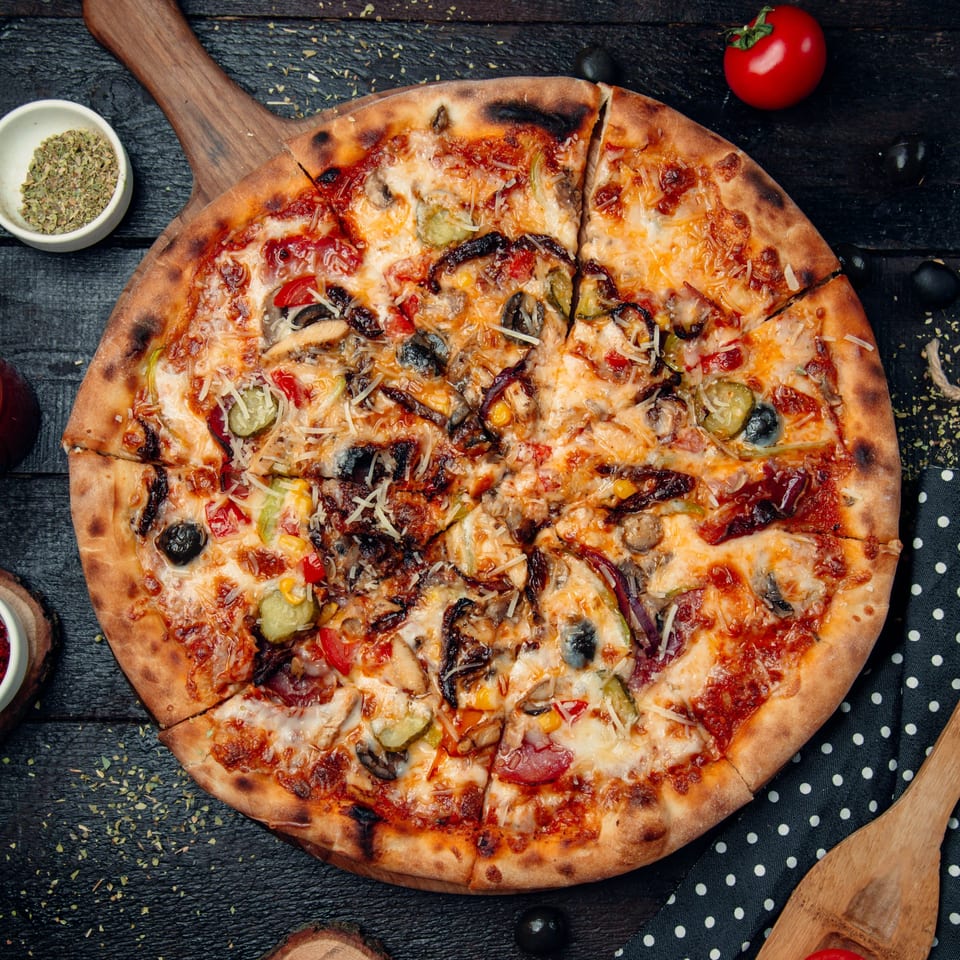 A Northwood House of Pizza & Subs pizza with various toppings, sliced on a wooden board.