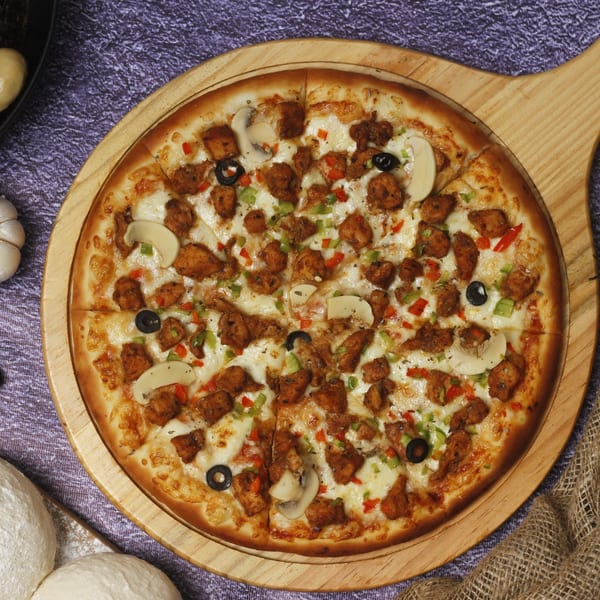 A Northwood House of Pizza & Subs pizza with chicken, mushrooms, olives, and peppers on a wooden board.